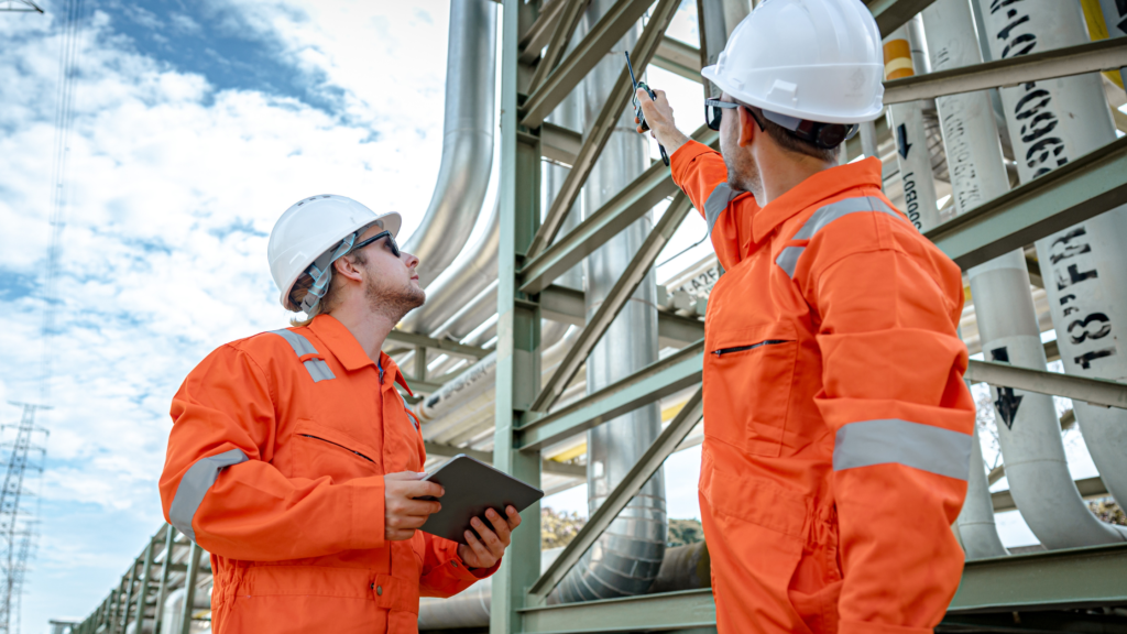 Two workers in overalls pointing at gas pipes.